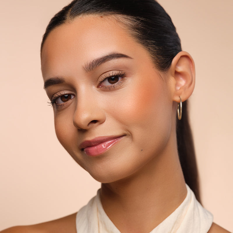 Frau mit peach Blush auf den Wangen für einen frischen Look