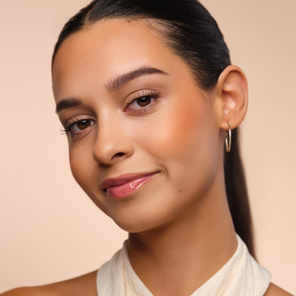Frau mit peach Blush auf den Wangen für einen frischen Look