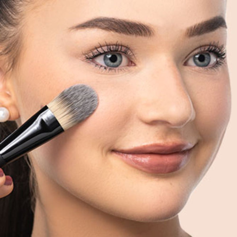 Frau trägt Foundation mit einem Make-up Pinsel auf 