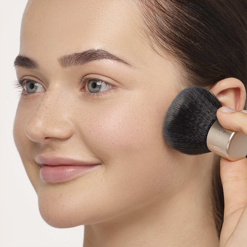 Frau bekommt Mineral Make-up mit einem Kabuki Brush aufgetragen