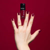 Dunkelrot lackierte Nägel auf dunkelrotem Hintergrund und dem Art Couture Nail Lacquer in N°705 - berry.