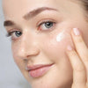 Ein Model trägt etwas Creme auf die Wange auf.