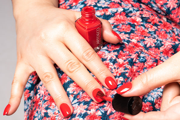 Es werden die Nägel mit einem roten Nagellack lackiert