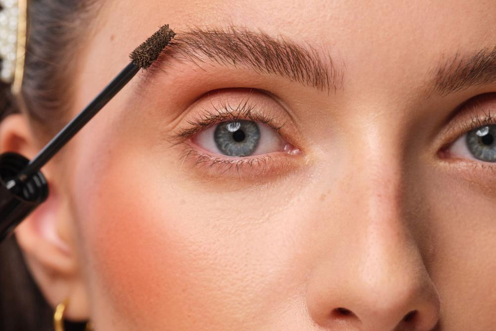 Close-up auf das Auge des Models. Es wird ein Augenbrauen-Gel auf die Augenbrauen aufgetragen um diese voller wirken zu lassen