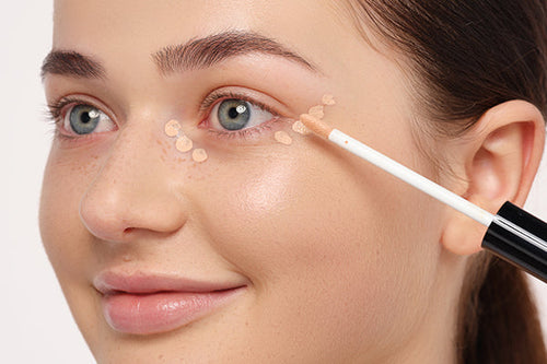 Ein Concealer wird unter den Augen aufgetragen