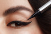 Ein Eyeliner wird vor einem geschminktem Augen gehalten
