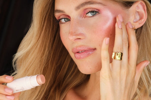 Model trägt glänzenden Highlighter auf den Wangenknochen auf und betont mit dem ARTDECO Glow Stick einen strahlenden Teint mit frischem Rosé-Finish für einen leuchtenden Teint.