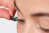 Einer Frau werden künstliche Wimpern auf die natürlichen Wimpern angelegt