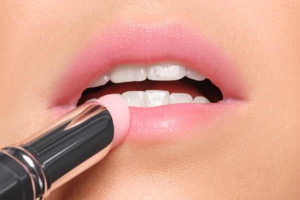 Lippen werden mit einem zart roséfarbenen Lip Balm geschminkt.