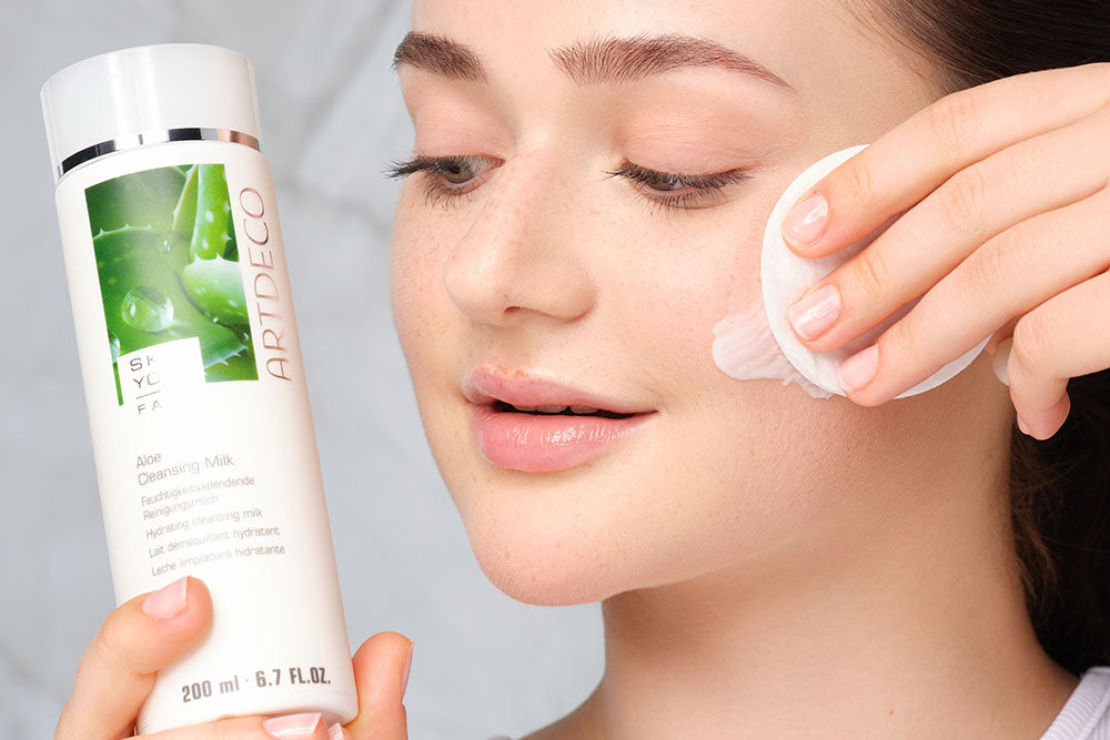 Das Gesicht wird mit einem Pad gereinigt, dabei hält das Model eien Cleansing Milk neben ihr Gesicht 