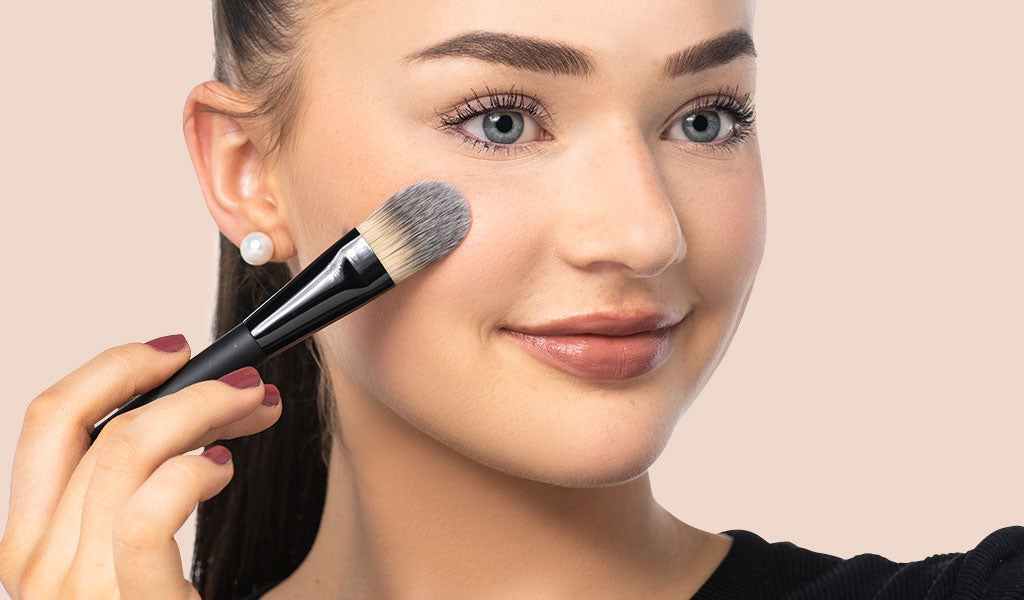 Frau trägt Foundation mit einem Make-up Pinsel auf 