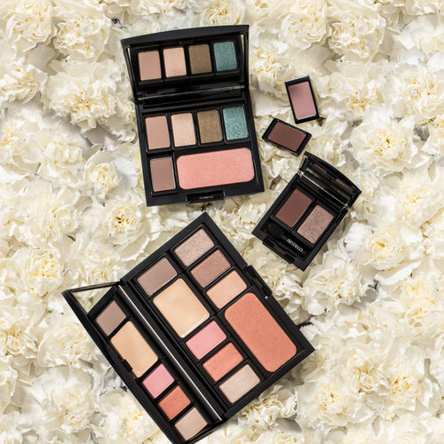 Eine befüllte Beauty Box liegt geöffnet auf einem Meer an weißen Blüten