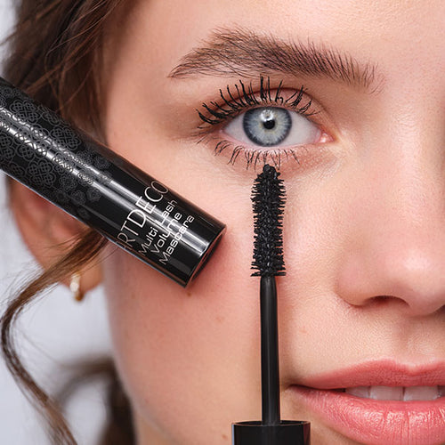 Close-up auf das Auge des Models, welche die Bürste der Multi Lash Volume Mascara an ihr Auge hält und der Effekt der Mascara gut sichtbar ist 