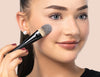 Frau trägt Foundation mit einem Make-up Pinsel auf 