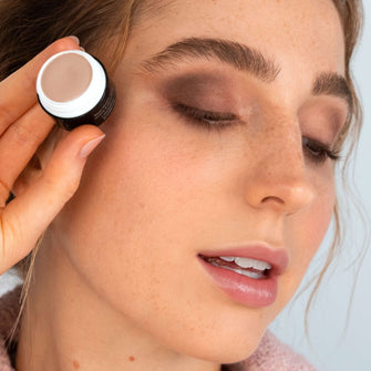 Frau mit rötlichen Haaren hält die ARTDECO Eyeshadow Base and ihre geschminken Augen