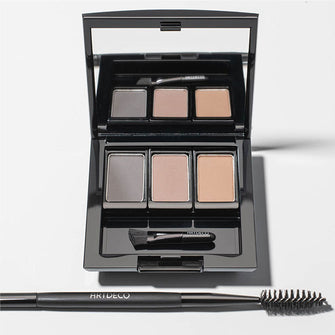 Eine Beauty Box Trio befüllt mit drei verschiedenen Eye Brow Powdern und Eye Brow Brush. Daneben ist ein 2 In 1 Brow Perfector platziert.