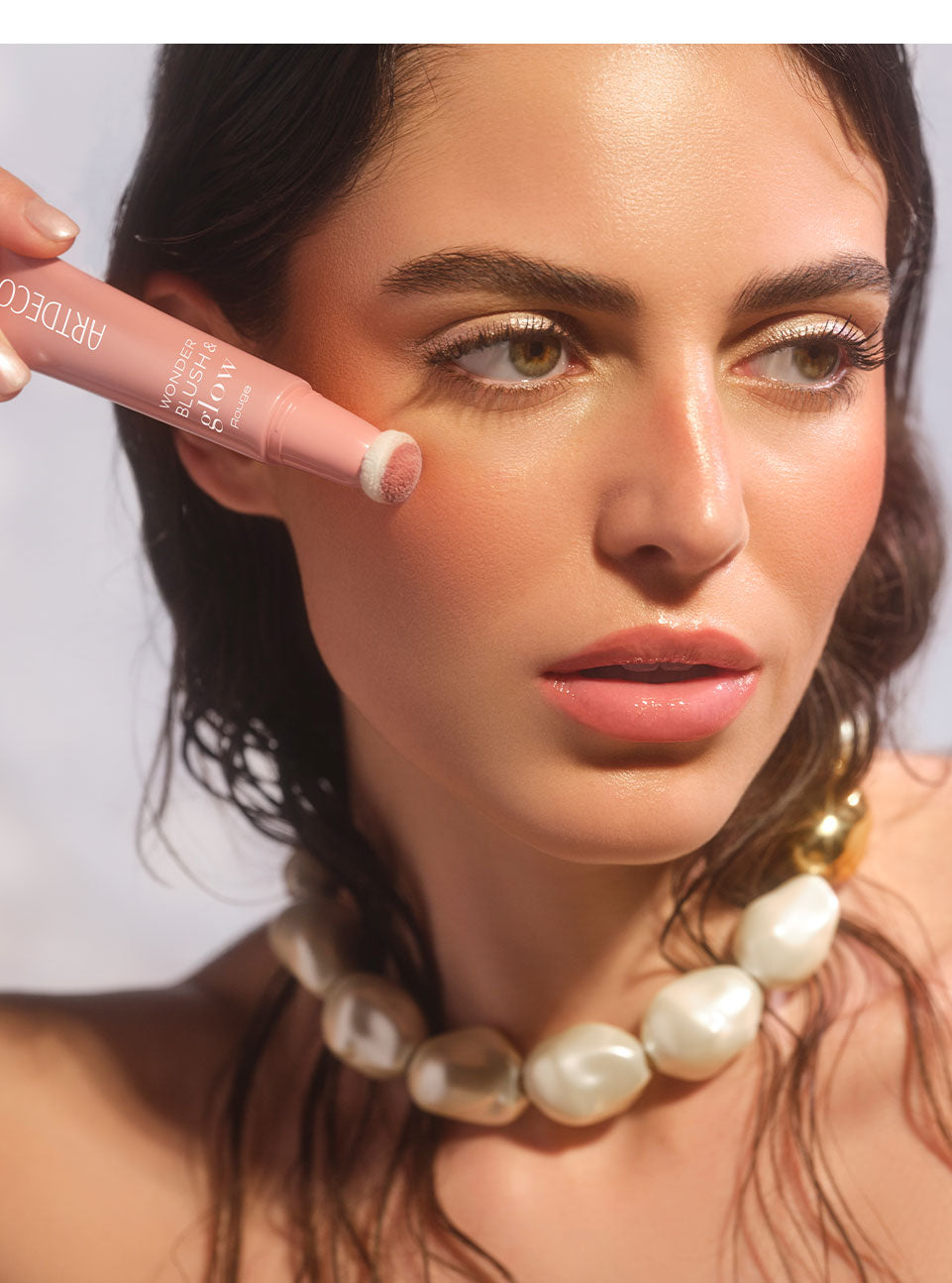 Brünettes Model mit glowy Make-up und einem natürlich, Frischen Teint trägt den Wonder Blush & Glow Rouge mit dem Schwämmchenapplikator auf ihre Wange auf, und dieses Ergebnis zu erzielen