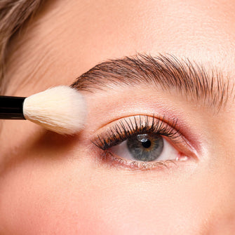 Blending Brush wird an ein geschminktes Auge gehalten.