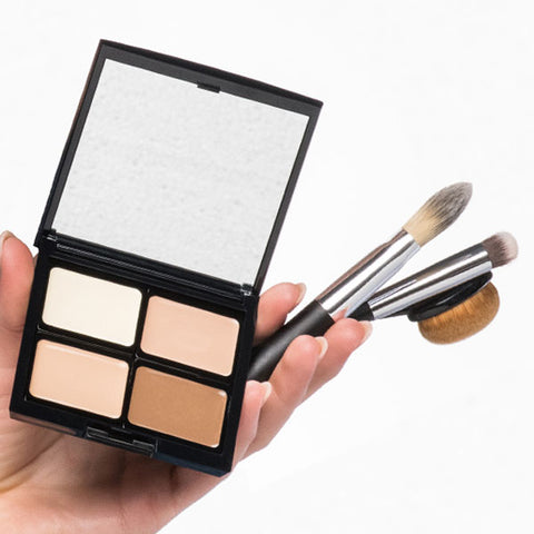 Hand hält Beauty Box mit vier verschieden Camouflage Creams und für das Produkt geeignete Pinsel