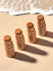 Hintereinander platzierte Bronzer Sticks auf Strandhintergrund.