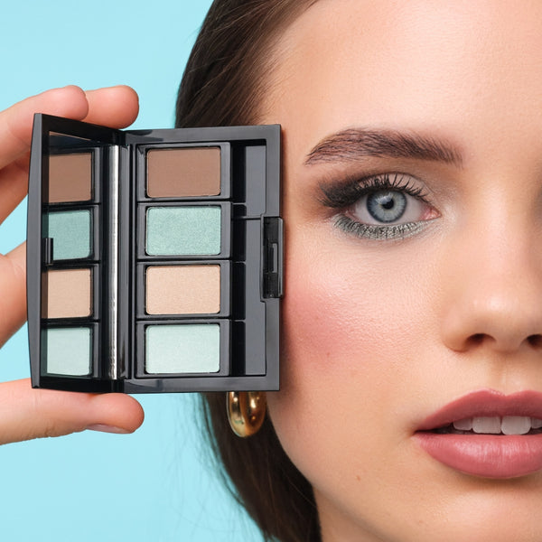 Model mit augenbetontem Make-up in Mintgrün und Taupe hält eine befüllte Beauty Box.