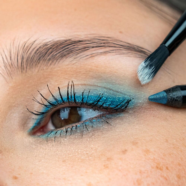 Glitzernder Eyeliner Look mit türkisem Eyeliner und Pinsel am Auge.