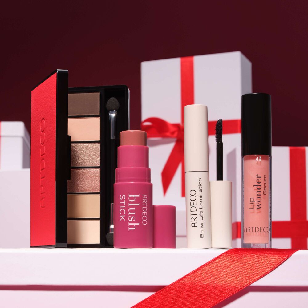 Vier von der Community ausgewählte ARTDECO Make-up-Produkte des Online Exclusive Adventskalenders: Iconic Eyeshadow Palette, Blush Stick, Brow Lift Lamination und Lip Wonder Serum, festlich inszeniert mit Geschenkboxen.