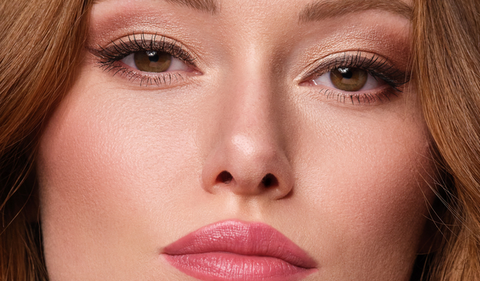 Frau mit natürlichen Make-up perfekt für das erste Date hält den Hydra Lip Booster in der Hand und trägt das Produkt auf ihre Lippen auf