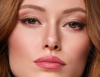 Frau mit natürlichen Make-up perfekt für das erste Date hält den Hydra Lip Booster in der Hand und trägt das Produkt auf ihre Lippen auf
